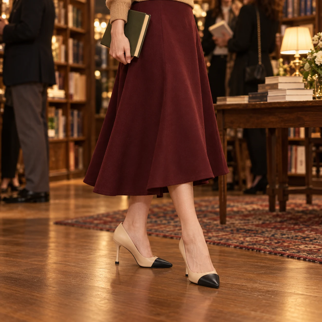 Petite woman wearing beige and black cap-toe heels with a burgundy skirt at a book launch
