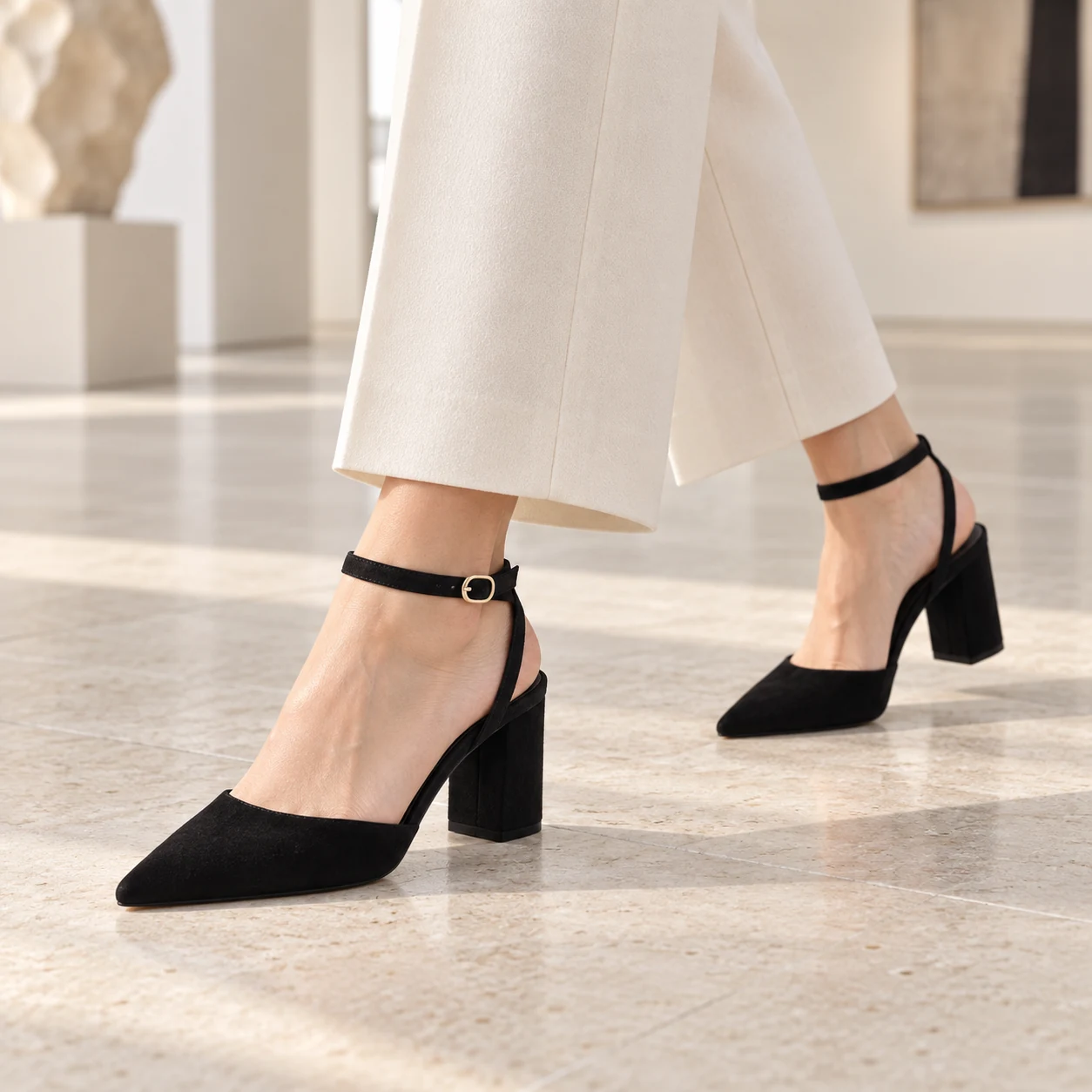 Woman wearing black suede Midnight Allure block heels with ivory cropped trousers