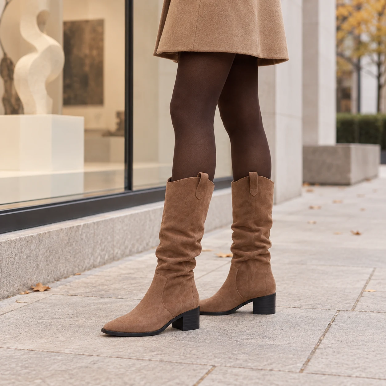 Petite woman wearing brown slouch boots with a camel skirt in an autumn gallery district
